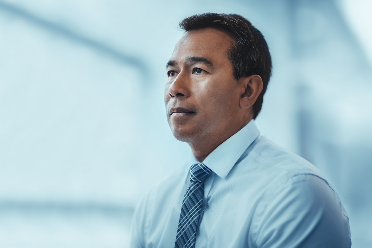 Portrait of Asian mature businessman serious looking away concerned thinking about future in business office in businesswear